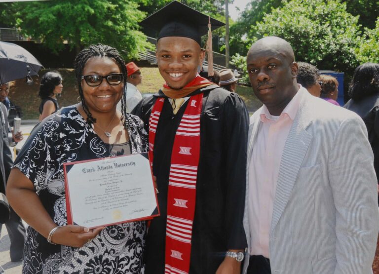 Image of Smiling Mom and Dad with Graduate son wearing cap and gown